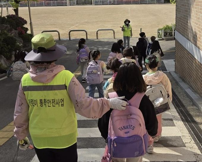 초등학교 학생들이 워킹스쿨버스 안전지도사와 함께 등교하고 있다.